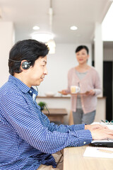 パソコンを操作する男性とお茶を運ぶ女性