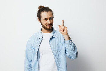 Young man with long hair wearing a light blue shirt showing a finger up, symbolizing a bright idea...