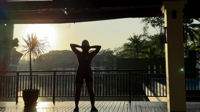 Silhouette of a woman exercising against the backdrop of a stunning sunrise, creating a peaceful and energizing scene filled with warmth and tranquility.