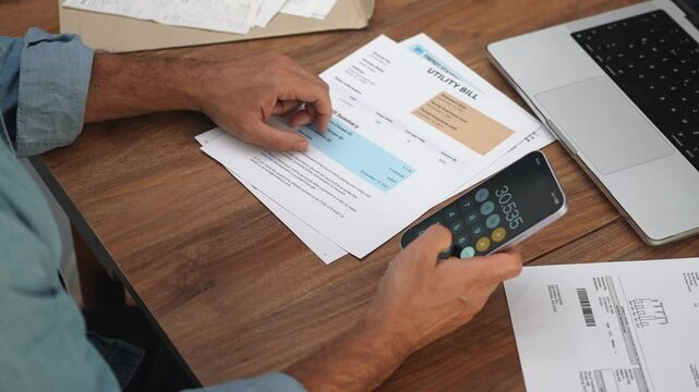 Adult man calculates total expenses examining utility bills, male family breadwinner conducts analysis of household expenditures summarizing financial data slow motion