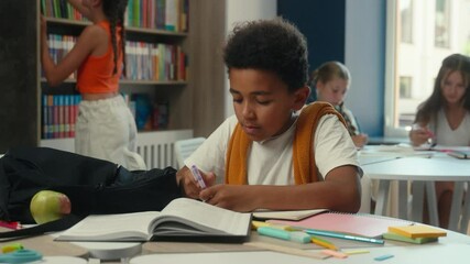 African American little boy child guy schoolboy pupil kid son primary elementary education student school lesson end writing in copybook studying learning at desk prepare study learn books in library