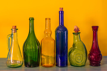 set of colourful vintage bottles sitting on the table against yellow background