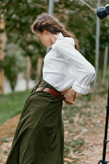 Fototapeta premium Elegant outdoor portrait of a female model wearing a white blouse and green skirt, showcasing natural beauty and emotional expressiveness in a serene garden background