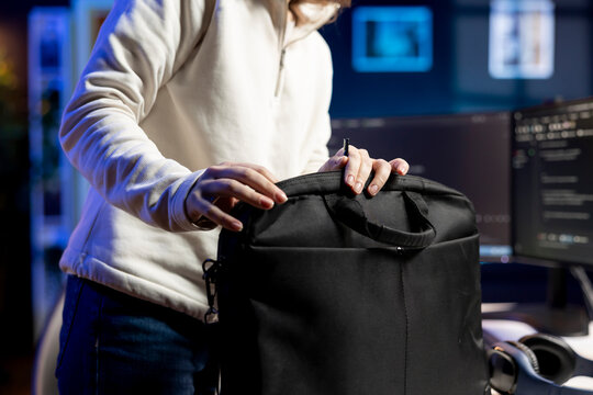 Developer closing laptop, ready to go home after designing and developing software applications. IT professional packing notebook in bag after implementing and maintaining company systems