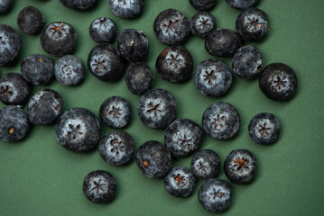 Fresh blueberries on a green surface.Blueberries have a dark blue color and a slightly rough texture.  A clear plastic container filled with blueberries.