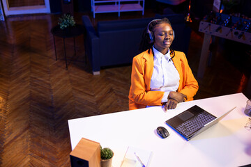 Ecstatic gen Z woman in RGB lit apartment listening music during relaxation time, feeling...
