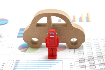 Business concept with miniature robot, car model, and financial graphs