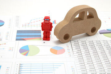 Business concept with miniature robot, car model, and financial graphs