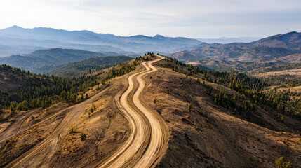 Environmental crisis. Winding dirt road through mountainous landscape under a clear sky.