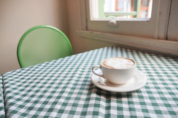 Warm cup of coffee on a checkered tablecloth in a cozy cafe