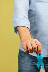 Holding a blue ribbon for prostate cancer awareness and support