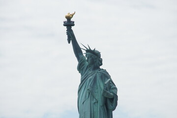 Fototapeta premium In New York, Manhattan, the Statue of Liberty stands tall, her torch held high as a beacon of freedom and a symbol of America. This landmark has long welcomed immigrants arriving in the New York