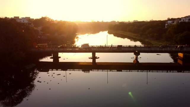 Busy road bridge above Godavari riverbank near Panchavati Hindu temple and Ganga Ghat in Nashik in beautiful sunset evening, Maharashtra, Aerial view