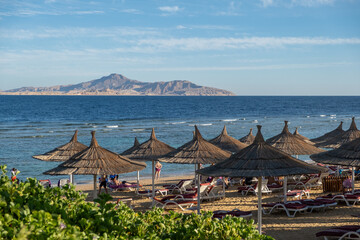 Relaxing beach atmosphere in Egypt with straw umbrellas and a distant island view