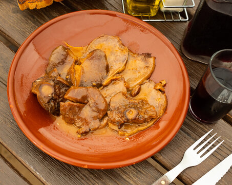 Veal calf meat is cooked with mushrooms saffron milk cap and cream, toasted crackers, baguette and glass of red wine are served with dish.