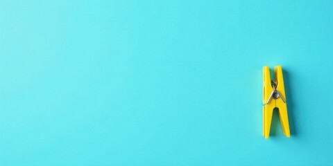 A single yellow clothespin rests on a vibrant blue background, a minimalist image ideal for various design applications and projects that require a simple yet impactful visual element.