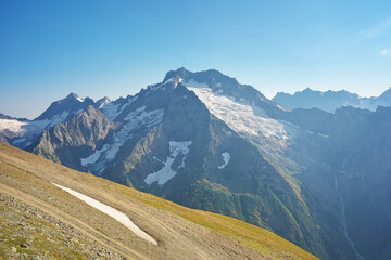 Fototapeta premium Dombay Ulgen mountain glacier and green medaow at day.
