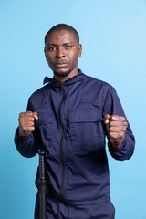 Fototapeta premium Confident security officer with fighting skills and experience posing in studio, standing with clenched fists ready to throw punches on duty. Guard protecting the premises, necessary safety measures.