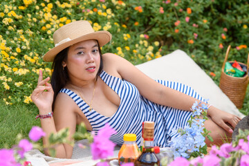 Fototapeta premium A stylish woman in a blue and white striped dress sits on a blanket, looking confidently at the camera.