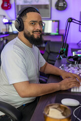 A focused man is immersed in his creative process, crafting music in his modern home studio with highquality gear and a vibrant atmosphere, wearing advanced noisecanceling headphones