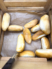 A wooden box with a bunch of bread rolls inside