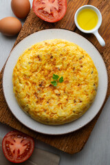 Overhead view of a traditional Spanish potato omelette on a wooden base.