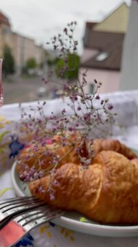 An aesthetic breakfast on the windowsill on a summer morning with a bouquet of flowers, croissants, a cocktail and flower tea