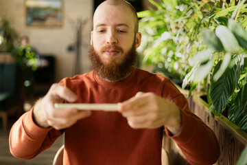 Bearded redhead man scanning remote check deposit while using mobile phone