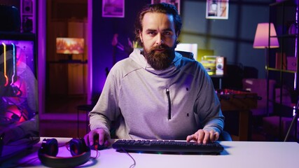 Pro gamer playing intense game, teaching audience professional esports players skills. Man in gaming chair talking with audience, filming tutorial in how to defeat enemies © DC Studio
