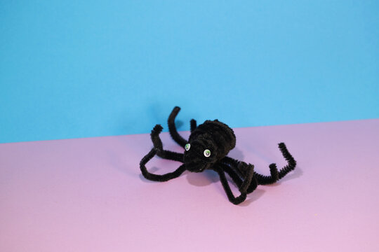 DIY Pipe Cleaner/DIY from Chenille Wire. A spider made from a pipe cleaner on a pink and blue background. Children's imagination. An idea for what to make with children in rainy weather.