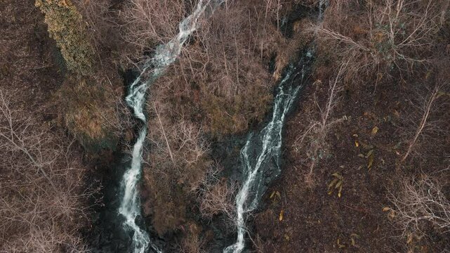 Waterfalls Flowing Through Fall Trees. aerial pullback shot