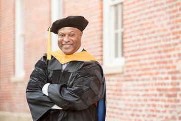 Smiling graduate in doctoral regalia standing confidently