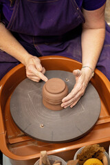 Artisan shaping clay on a pottery wheel in a ceramics studio