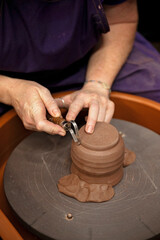 Artisan trimming a clay piece on a pottery wheel using a loop tool