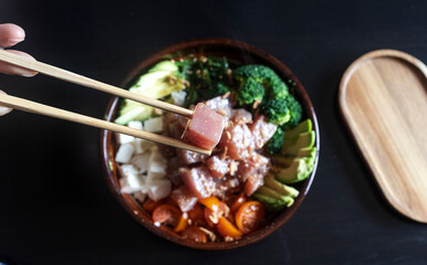 Hand using chopsticks lifting piece of tuna sashimi