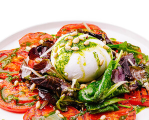 Salad with fresh tomatoes and creamy cheese on a white plate