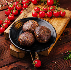 Savory meatballs served on a wooden board with fresh tomatoes