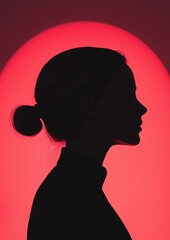 Silhouette of a woman's head and neck. the woman is facing towards the right side of the image, with her head turned slightly to the left. she has her hair tied up in a bun on top of her head.