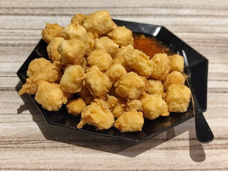 Crispy fried tofu served with sauce. Crispy fried tofu served with chili sauce on a black plate. Know the crispy tofu served at the cafe.