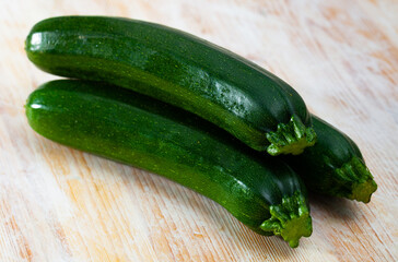 Whole and sliced fresh zucchini on wooden table. Healthy vegetarian ingredient