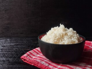 Nasi putih or white rice in bowl with black wooden table background, Darkness concept 