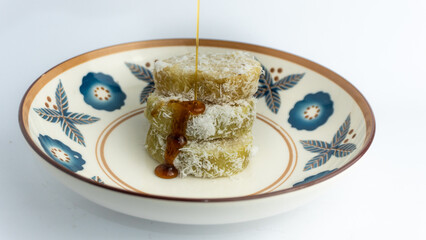 Lupis is a traditional Indonesian food, with the main ingredients being white sticky rice, grated coconut and melted palm sugar. served on a plate