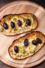 Bruschetta with mozzarella and cheddar cheese, olive pesto and kalamata olives. on wooden...