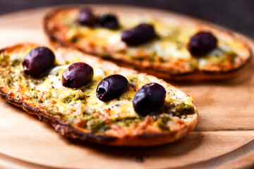 Bruschetta with mozzarella and cheddar cheese, olive pesto and kalamata olives. on wooden background. Soft focus. Close up