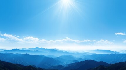 Panoramic view of a mountain range under a bright sun with clear blue sky and lush green valleys