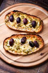 Bruschetta with mozzarella and cheddar cheese, olive pesto and kalamata olives. on wooden background. Soft focus. Close up