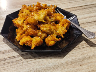Crispy broccoli with chili sauce served on a black plate. Crispy broccoli with chili sauce served on a black plate, served in a cafe.