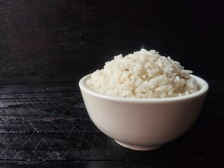 Nasi putih or white rice in bowl with black wooden table background 