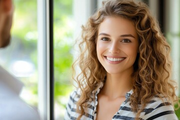 Obraz premium Woman with curly hair smiles warmly in a bright room during a casual conversation