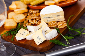 Sliced blue cheese served with walnut croutons and arugula at table